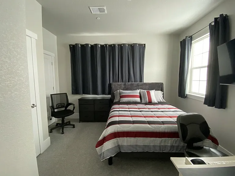 1st floor bedroom with queen-sized bed, desk, and 50# TV.