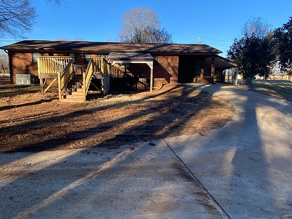 back of house with carport and deck.
with concrete parking,