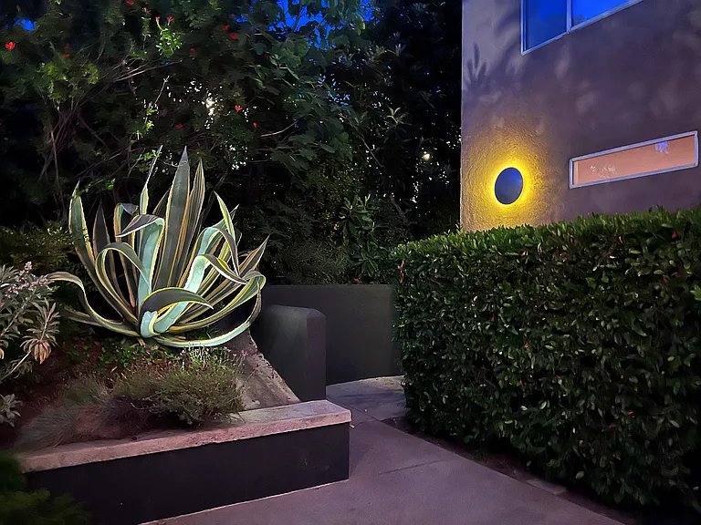Beautifully landscaped communal garden featuring secure gated entry, custom design elements, and ambient night lighting.