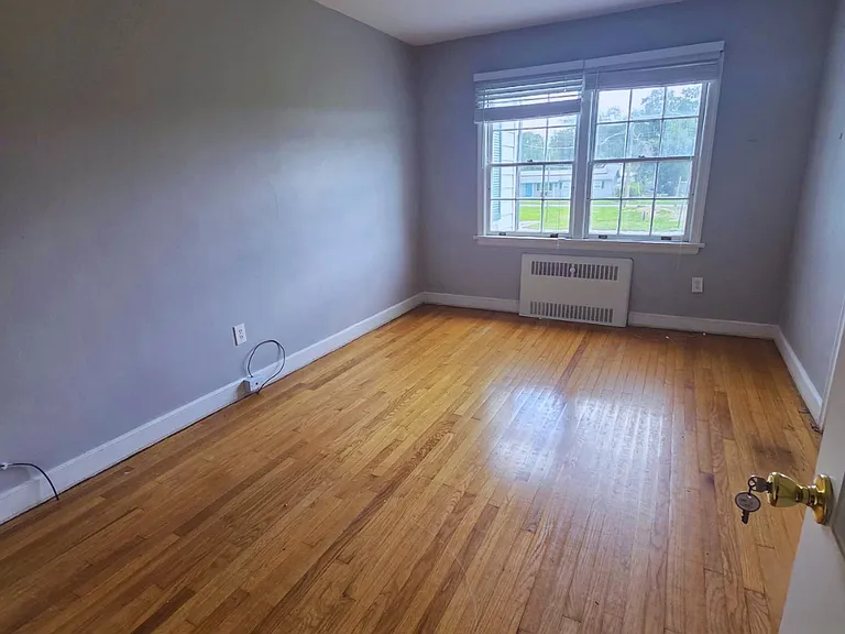 Well-lit bedroom with large windows, hardwood floors, and cozy ambiance.