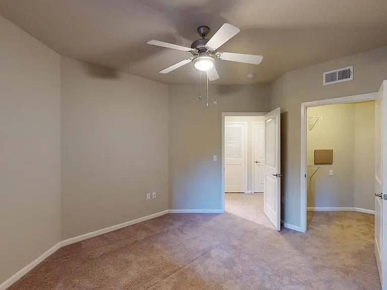 Spacious apartment bedroom with large closet and carpet floor.