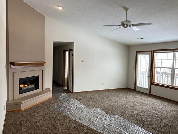 View of part of great room including fireplace, hallway to bedrooms/bathroom, and door/windows to balcony.