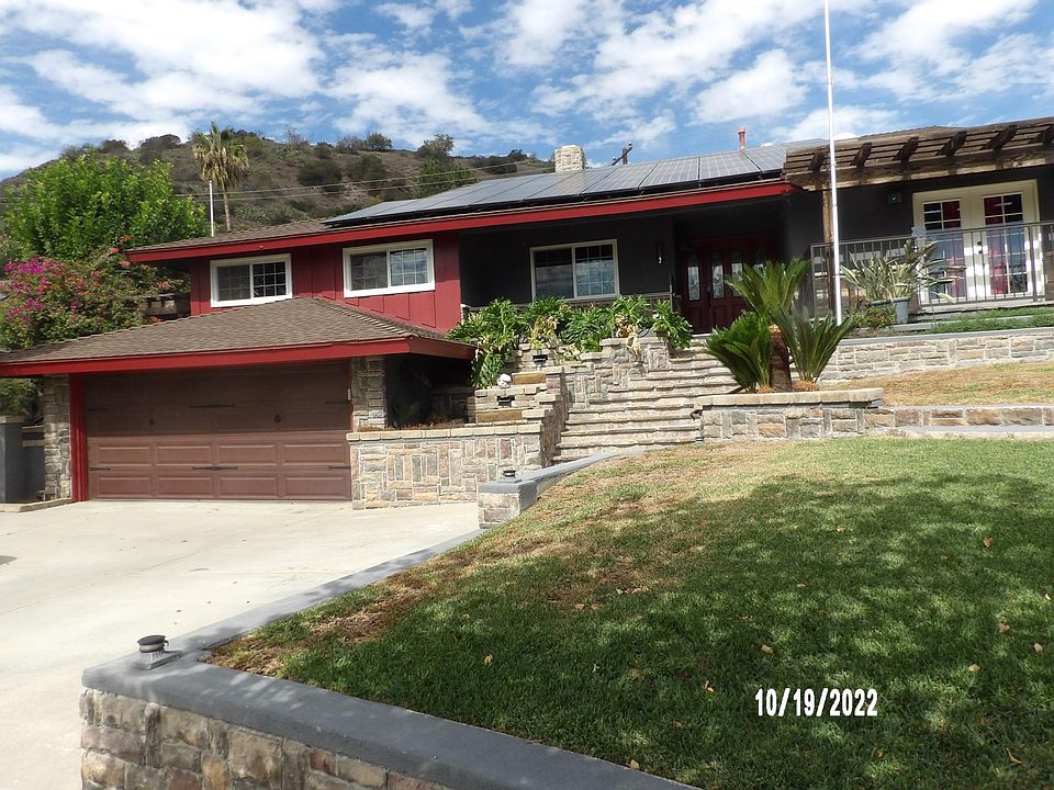 front view with lush gardens and garage.