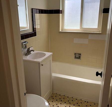 Bright, clean bathroom with medicine cabinet. Curved shower rod for bathing comfort and frosted windows for privacy.