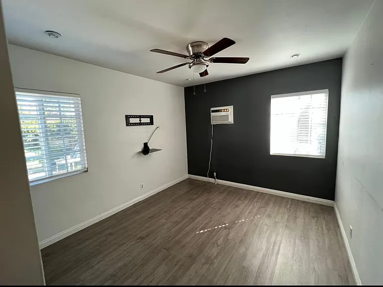 Primary bedroom, ceiling fan, wall ac unit, window blinds, built-in storage & closet.
