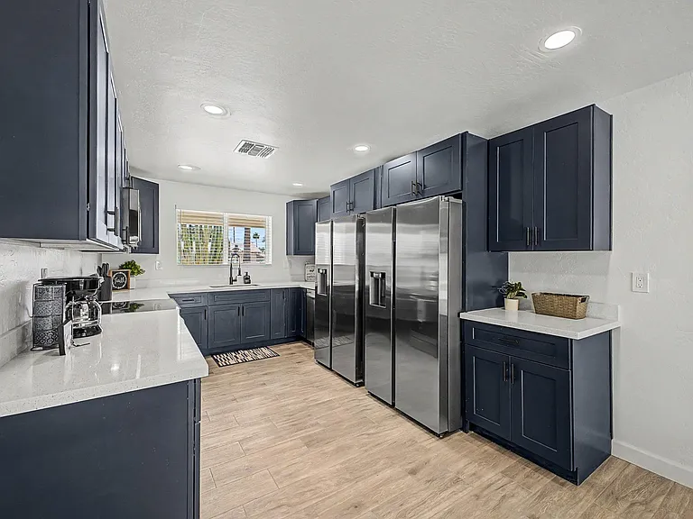 Spacious kitchen with ample navy cabinetry, generous counters, and stainless steel side-by-side fridges for easy meal prep.