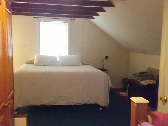 Upstairs is a bedroom with vaulted beamed ceiling. Flooring is a combination of parquet and carpet. Carpeting to be replaced prior to new tenant moving in.