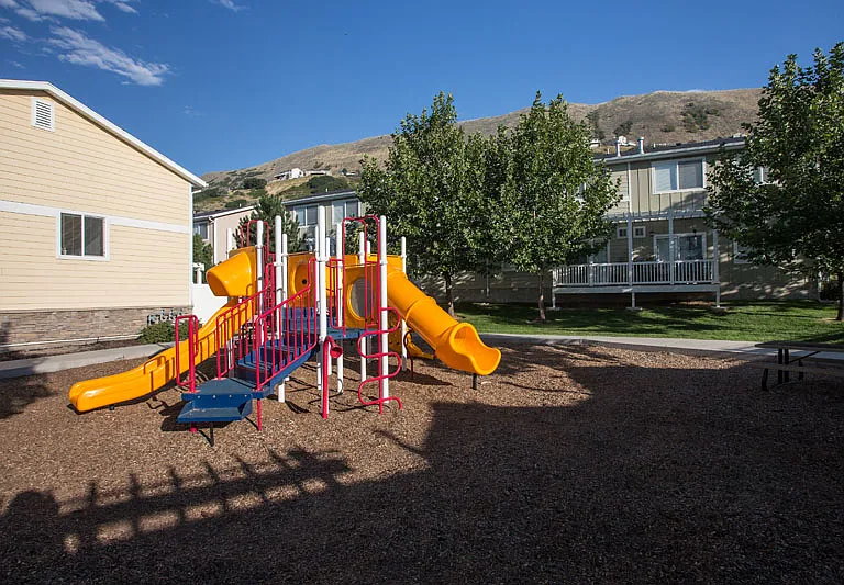 Liberty Hill Apartments, Draper, Utah, playground with a yellow slide and red and blue play equipment.