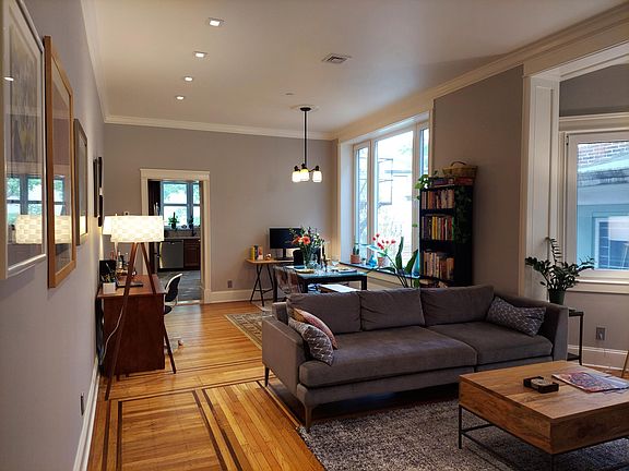 Living / Dining room looking south to the Kitchen. Walnut inlay oak floors, crown molding, and deep stone sills. 3-pane windows throughout.
