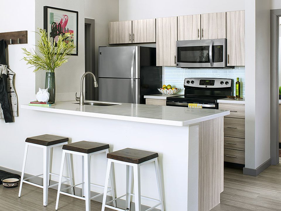 Apartment Kitchen with Stainless Steel Appliances, quartz counters and wood-like floors.