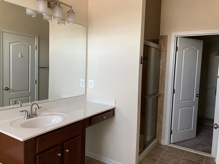 Luxury master bathroom with separate vanities, soaking tub, tiled shower, private toilet, and walk-in closet.