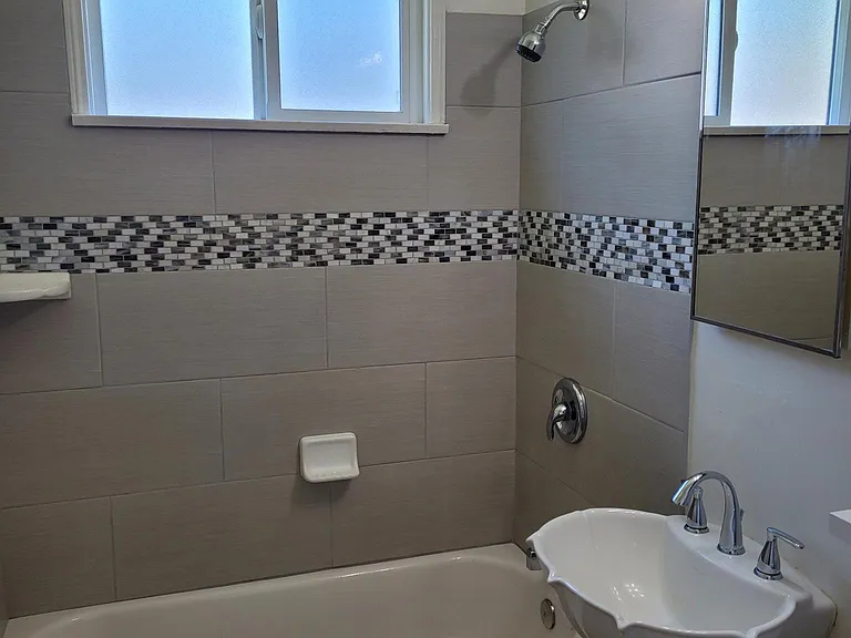 Bathroom with pedestal sink and tile tub surround.