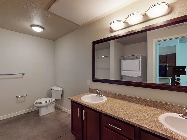 Apartment bathroom with polished concrete flooring and double sinks.