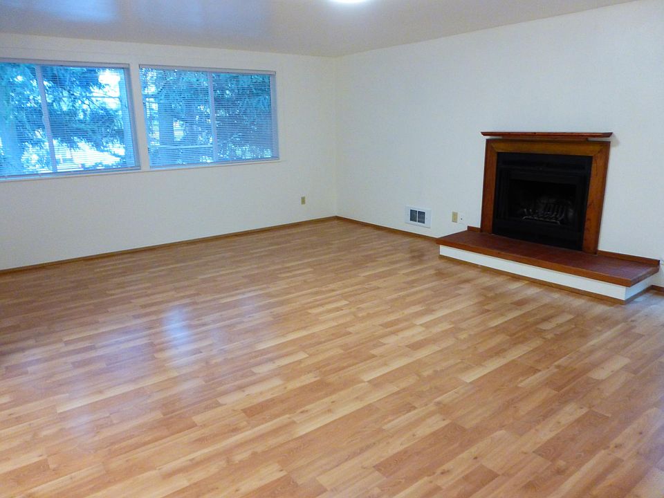 Spacious open living room with large windows and cozy fireplace for winter nights.
