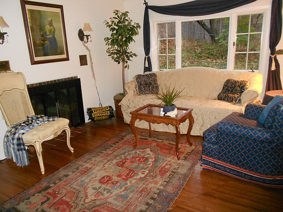 Living room has sofa, easy chair, picture window overlooking big grassy field