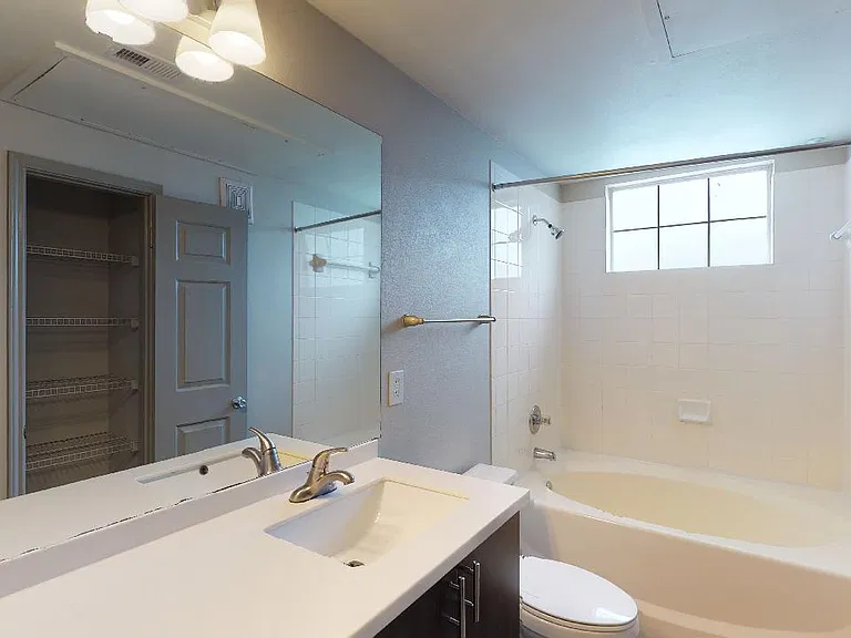 Apartment bathroom with large soaking tub and wood-style flooring.