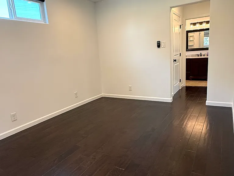 Primary bedroom featuring two windows, dimmable recessed LED lighting, a ceiling fan, a walk-in closet, and an en-suite bathroom.