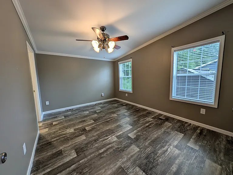 Master bedroom with master bath to the left. Two windows, ceiling fan and larger lighted walk in closet