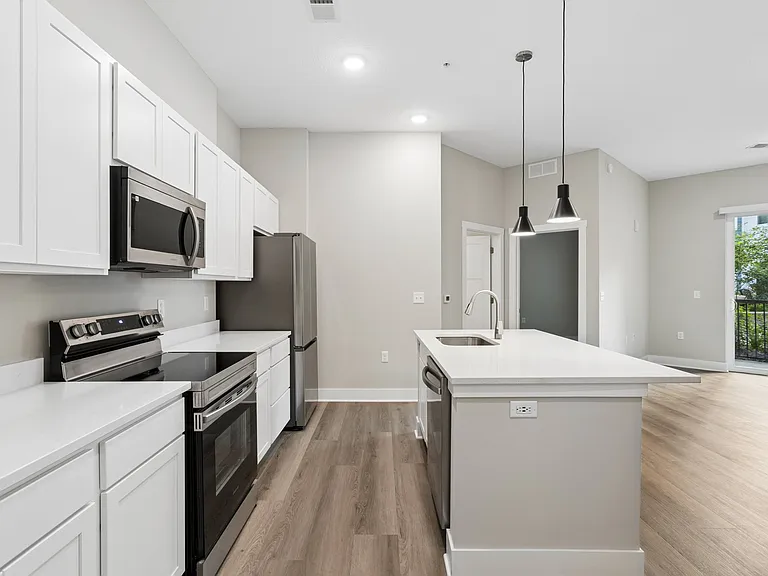Kitchen with appliances and living area of an apartment home at Tiffany Flats in Columbus, OH.
