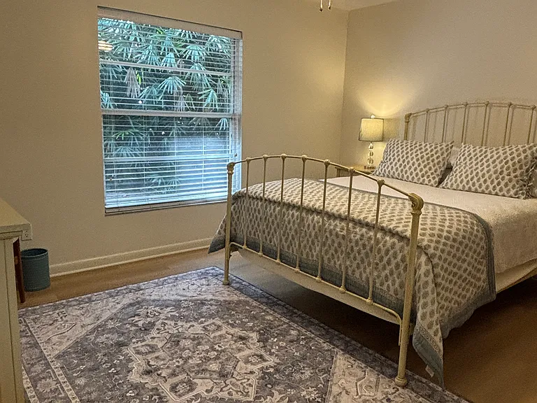Queen bed with a view of the private backyard with lush foliage.