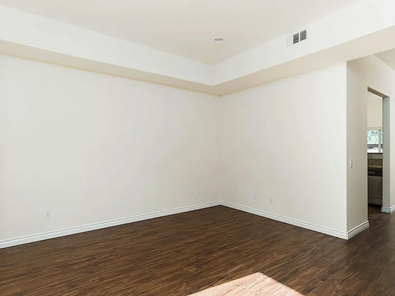 Living room with wood style laminate flooring, windows and access to private porch at The Nines Townhomes in Escondido, California.