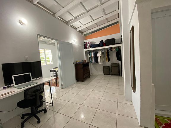 Main bedroom with closet, dresser, desk, smart tv, and sleeping area to the right.