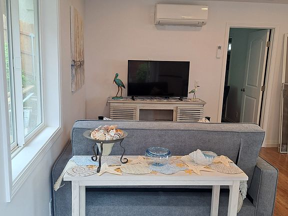 Enter into living room with recessed lighting. Entry Table, Laminate Flooring, Mini Blinds, Heating/Air Conditioning Unit. WiFi and Sofa which folds out into a second bed