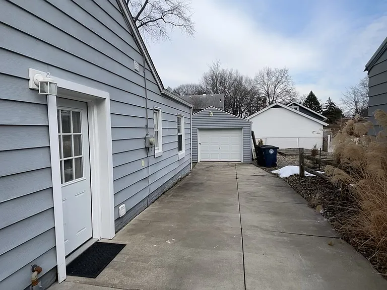 Wide, private concrete driveway leading to a (1) one car garage with lock and security lighting.