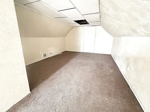Bonus bedroom with vaulted ceiling and carpet