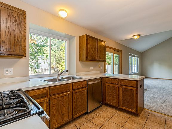 Kitchen with greenhouse window, stainless steel appliances and tile floors.
