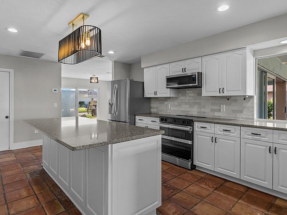 Large modern kitchen features new stainless appliances, huge eat-in island, solid-surface countertops, and cabinets with pull-out storage.