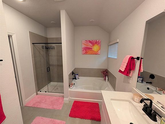 Bathroom featuring a bath, a stall shower, vanity, and lofted ceiling