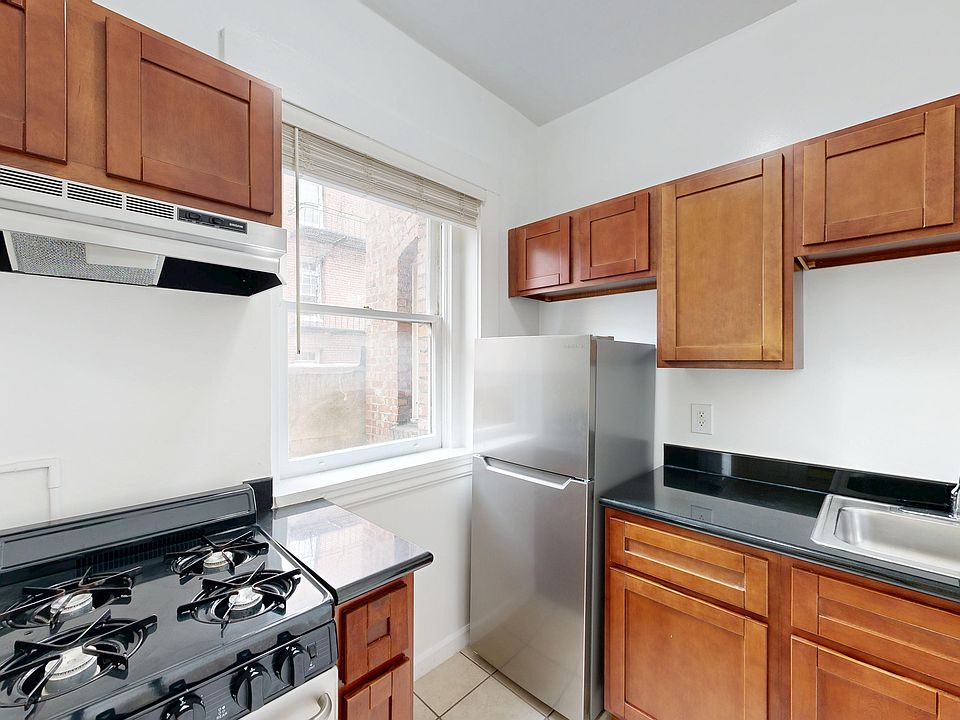 Kitchen featuring wood cabinetry, a stainless steel refrigerator, countertops, and a gas stove with a vent above