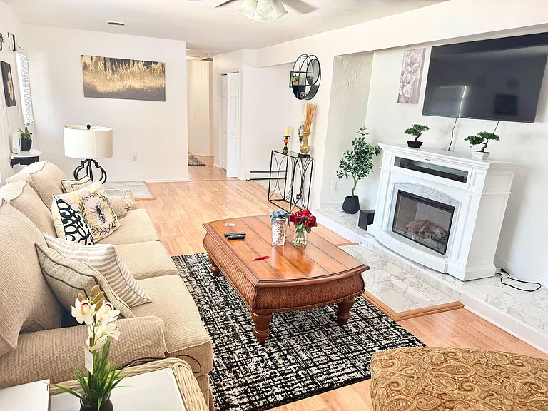 Inviting living room with a sectional sofa, large wall-mounted TV, and a fireplace with surround for added comfort.