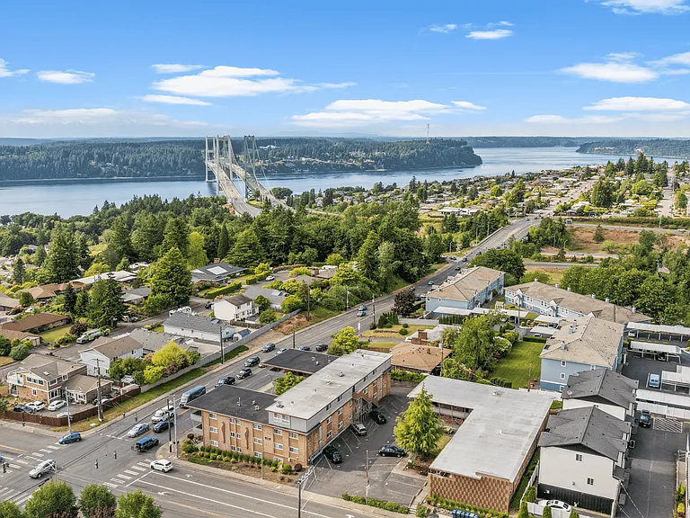The iconic Tacoma Narrows Bridge connects Tacoma to the Kitsap Peninsula, surrounded by scenic residential neighborhoods and lush greenery.