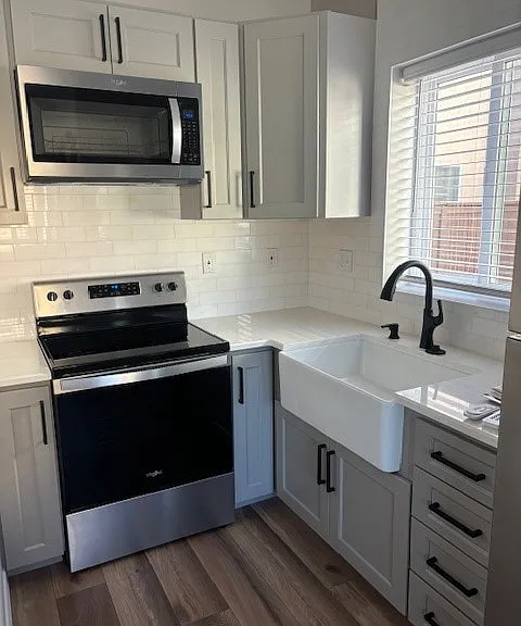 Kitchen featuring a farm house sink, full-sized refrigerator w/ freezer, stove/oven, and microwave.