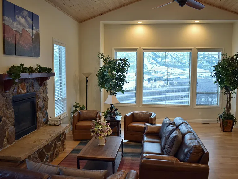 Stunning mountain views of Nordic Valley Ski Resort from your spacious living room. This inviting space features large windows for natural light, a cozy fireplace, recessed lighting, and a ceiling fan, creating the perfect atmosphere for relaxation