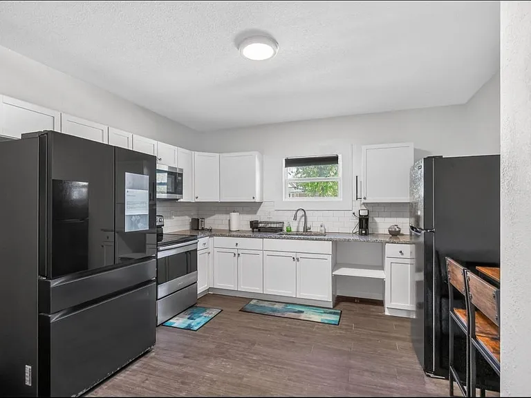 Functional kitchen with ample white cabinetry, full-size appliances, and a window over the sink for natural light.
