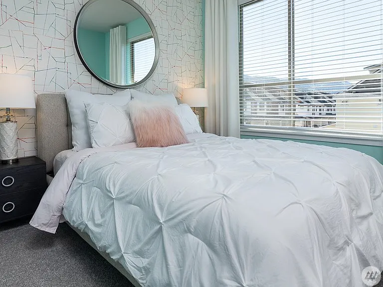 Comfortable secondary bedroom with large windows, abundant natural light, soft carpeting, and a spacious closet - offering a bright and relaxing space for family or guests.