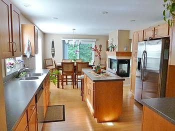 Gorgeous kitchen with Schrock maple cabinets, large custom island and solid Hawaiian bamboo flooring and stainless appliances (refrigerator does not stay). 