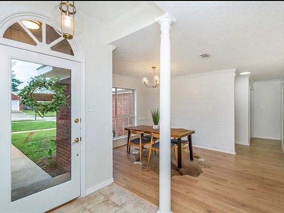 Foyer with a notable chandelier, light wood-type flooring, and ornate columns