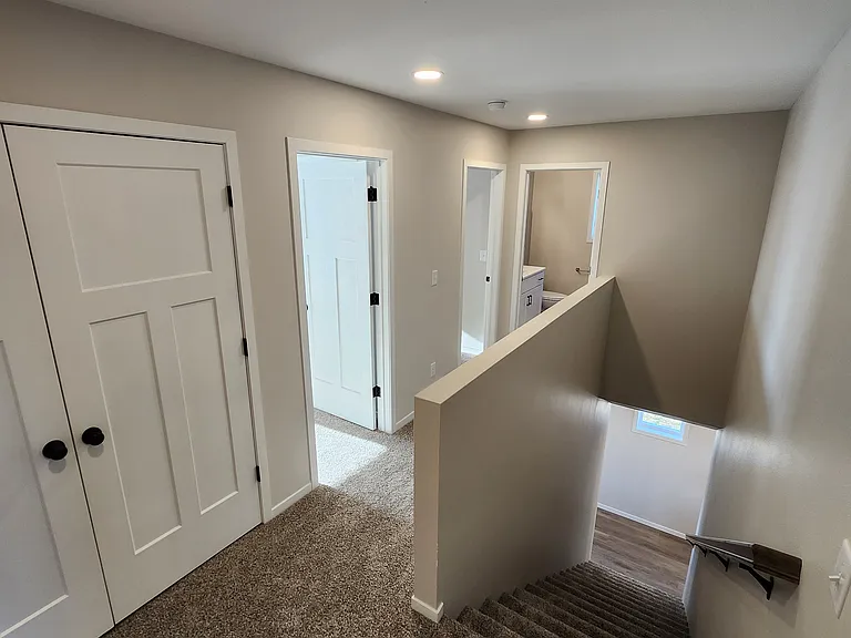 Upstairs landing looking to laundry space, second and third bedrooms and full bath. (Pictures are of another unit with similar finishes and features.)