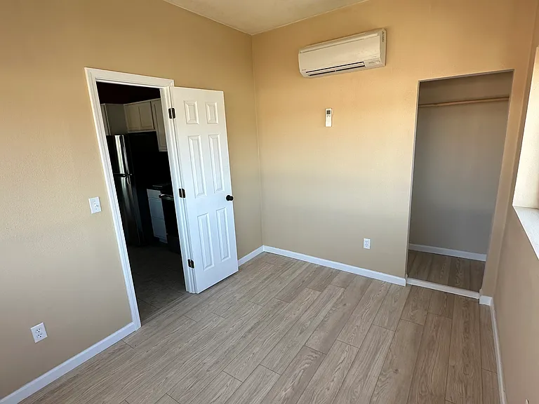 This bedroom has big bay windows. It goes into the kitchen.