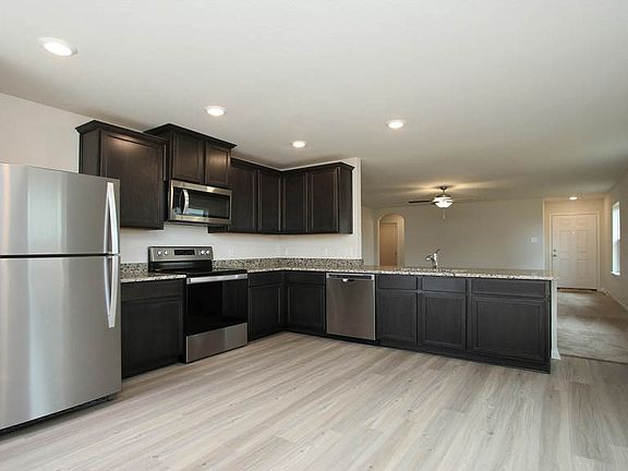 The open kitchen features polished granite counters, wood cabinets and an eat-in breakfast area.