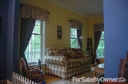 Formal living room features bright paint, four windows and crown molding.