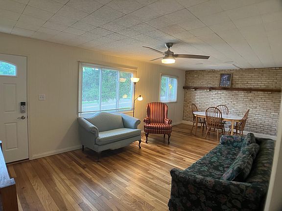 living room with dining table and brick accent wall with mantle