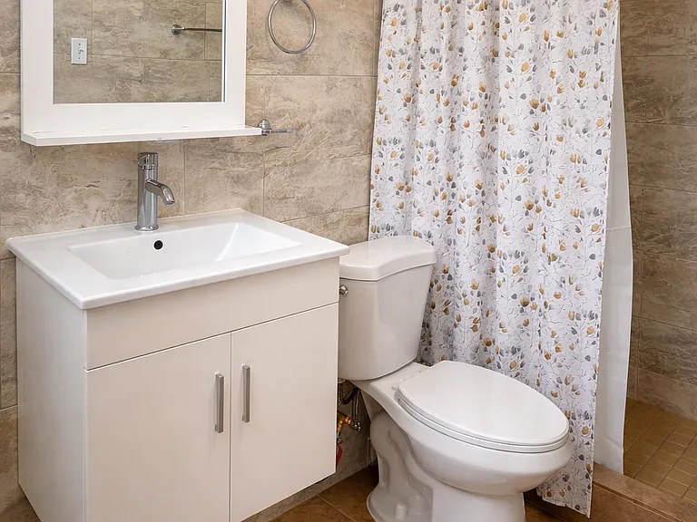 Freshly updated bathroom with modern vanity and neutral tiling.