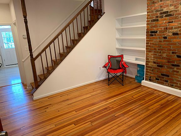 Living room with original floors and exposed brick.
