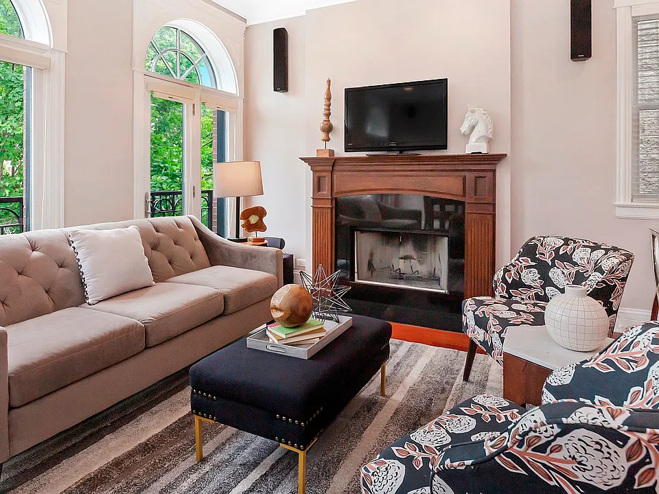 Large living room with wood burning fireplace and tree top views.