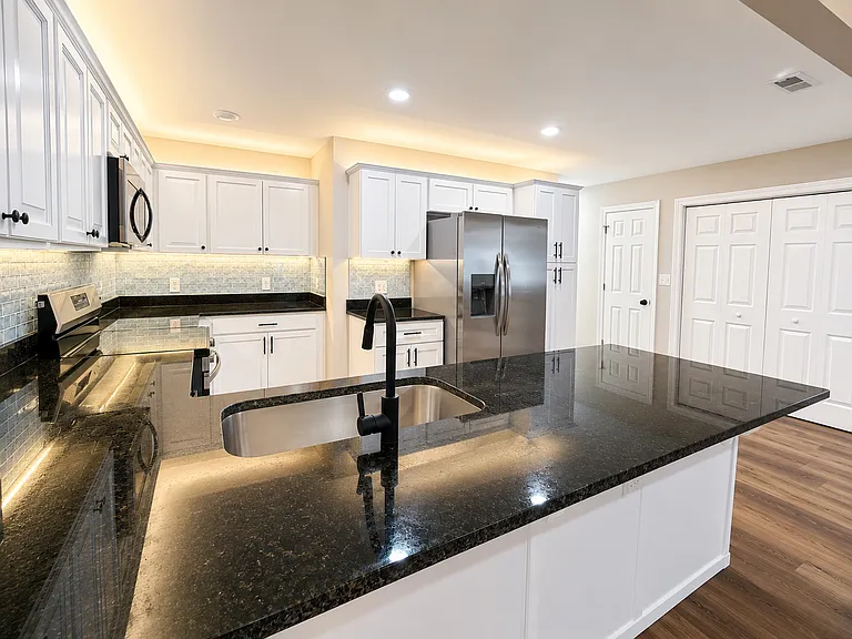 Kitchen with LED under & over cabinet lighting. Black granite countertops.